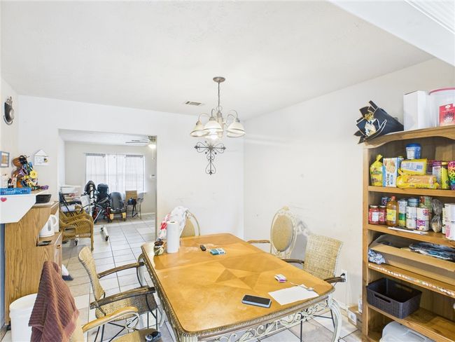 Dining space with light tile patterned flooring and a chandelier | Image 5