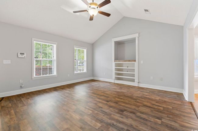 Spare room featuring a ceiling fan, lofted ceiling, dark wood-style floors, and baseboards | Image 6