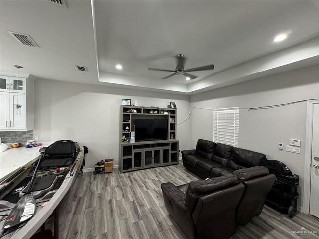 Living room with a ceiling fan, a tray ceiling, wood finished floors, recessed lighting, and baseboards | Image 7