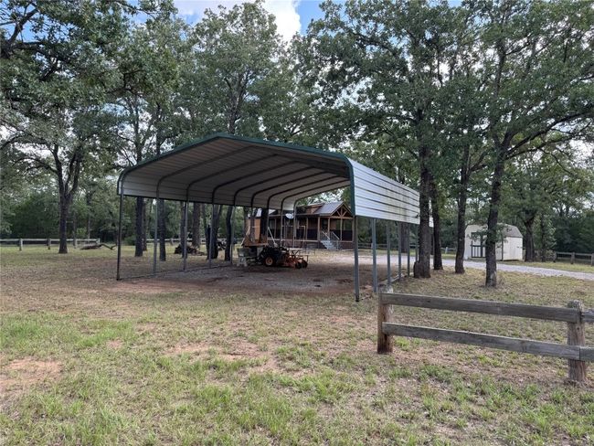View of property's community with a carport, a shed, and view of wooded area | Image 25