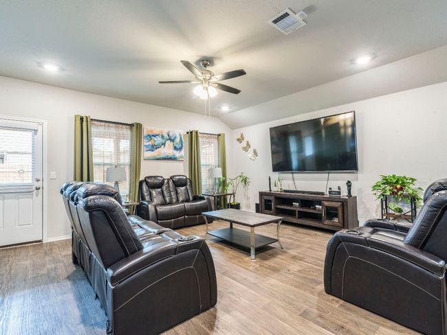 Living area featuring vaulted ceiling, visible vents, wood finished floors, and a ceiling fan | Image 12