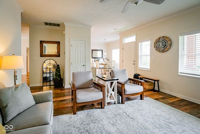 living room featuring crown molding, wood finished floors, ceiling fan, plenty of natural light, and baseboards | Image 6