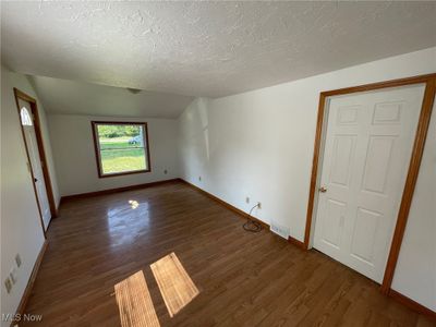 Empty room featuring a textured ceiling, dark hardwood / wood-style floors, and lofted ceiling | Image 2