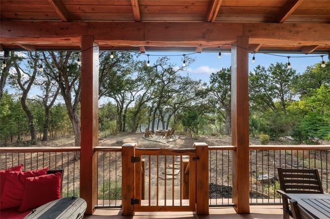 This gated back deck offers a perfect transition from indoor comfort to outdoor adventure. Overlooking a fire pit area and surrounded by lush trees, it's an inviting space to relax and enjoy nature, day or night. | Image 20