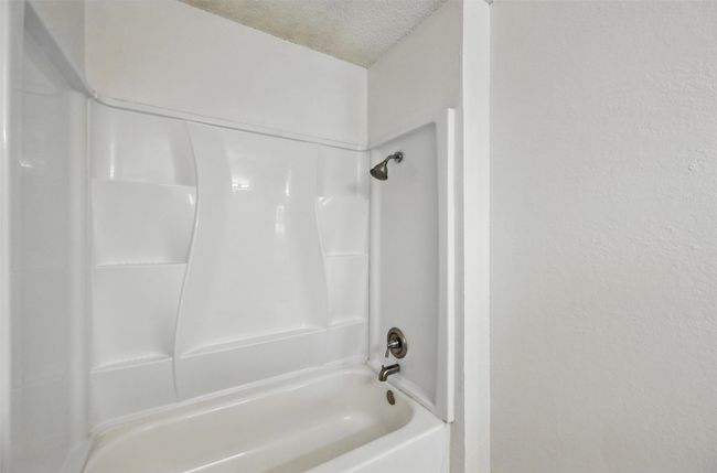 Full bath featuring a shower, a textured ceiling, and a textured wall | Image 17