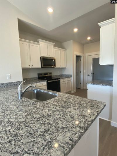 The kitchen features granite countertops and a full suite of stainless steel appliances. | Image 2