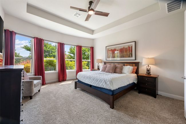 Carpeted bedroom with a raised ceiling, multiple windows, and a ceiling fan | Image 16