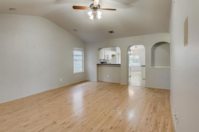 Unfurnished living room with ceiling fan, vaulted ceiling, light wood-style floors, arched walkways, and baseboards | Image 7