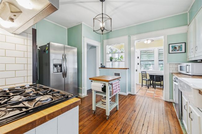 Kitchen featuring stainless steel refrigerator with ice dispenser, white microwave, butcher block countertops, gas stovetop, and ornamental molding | Image 12