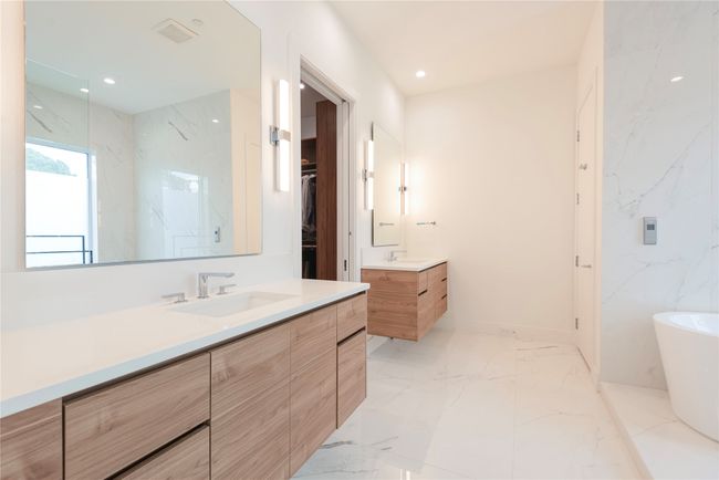 Primary bathroom featuring two vanities, a soaking tub and walk-in shower. | Image 13
