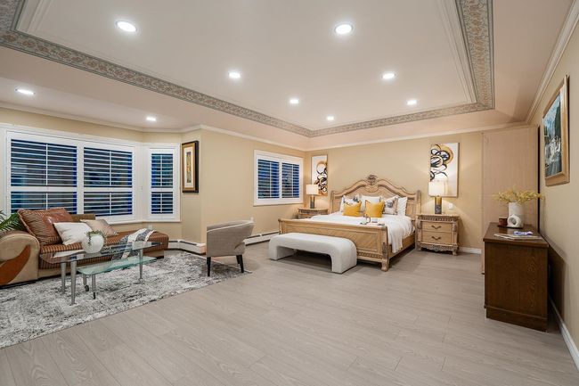 Bedroom featuring baseboards, a baseboard heating unit, crown molding, light wood-type flooring, and a tray ceiling | Image 18