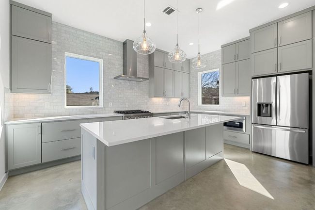 Kitchen with gray cabinets, stainless steel fridge, Deep sink, exhaust hood, Dishwasher, Microwave | Image 11
