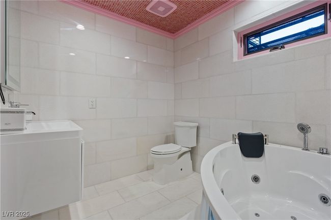 Bathroom with crown molding, tile walls, toilet, a whirlpool tub, and tile patterned floors | Image 66
