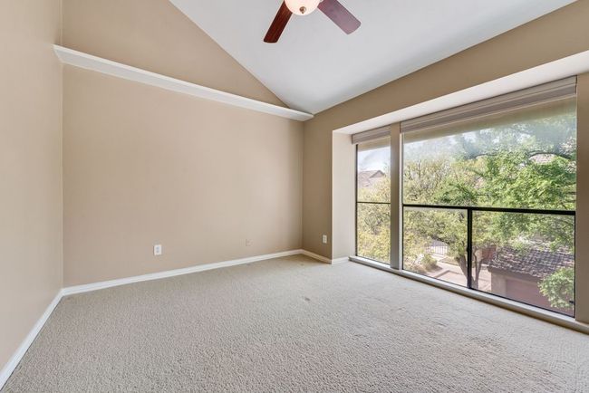 Carpeted spare room featuring ceiling fan, vaulted ceiling, and baseboards | Image 18