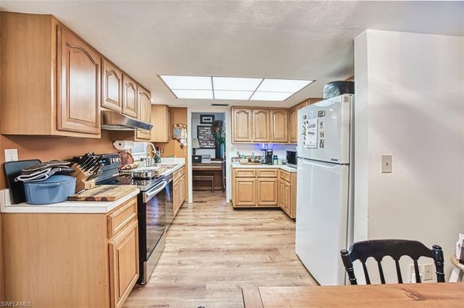 Kitchen with electric range, freestanding refrigerator, under cabinet range hood, light wood-type flooring, and light countertops | Image 16