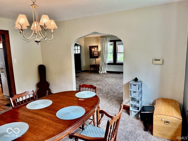 carpeted dining space with arched walkways and a chandelier | Image 16