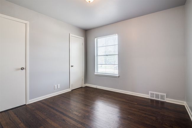 Unfurnished bedroom with dark wood-type flooring, baseboards, and visible vents | Image 20