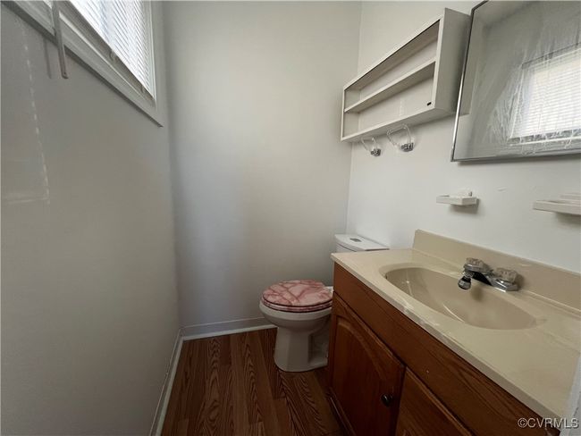 Half bathroom with toilet, baseboards, wood finished floors, and vanity | Image 4