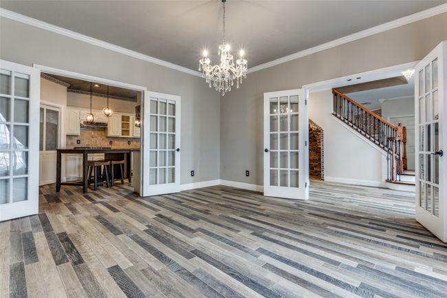 Spare room with wood finished floors, stairway, french doors, and a chandelier | Image 5