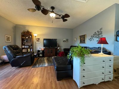 Living room featuring ceiling fan, wood-type flooring, and a textured ceiling | Image 3