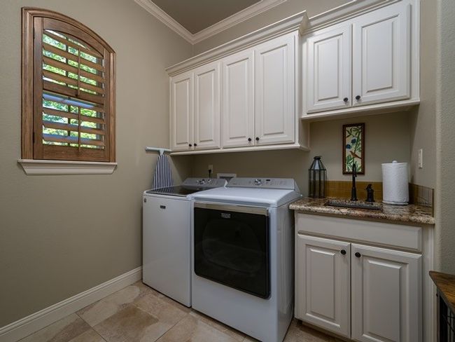 Laundry area featuring washer and clothes dryer, ornamental molding, a sink, baseboards, and cabinet space | Image 15