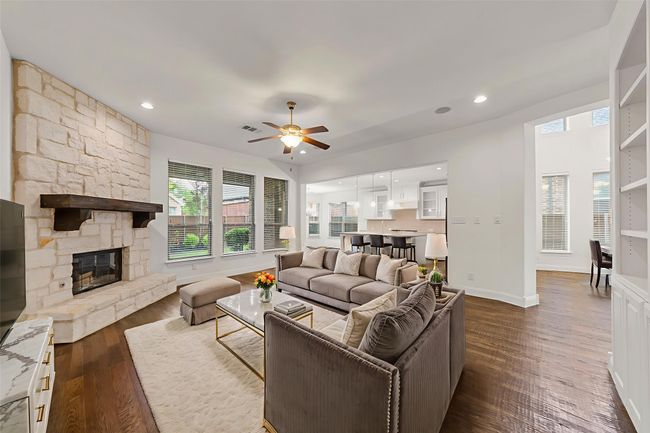 Living area featuring a ceiling fan, dark wood-style floors, a fireplace, and recessed lighting | Image 16