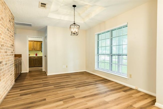 Formal Dining Room with wet bar is adjacent to the kitchen. LVP throughout the living spaces of the home. Accent tray ceiling with farmhouse style chandelier. | Image 7