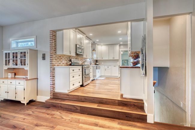 Kitchen featuring appliances with stainless steel finishes, light wood-type flooring, white cabinetry, recessed lighting, and decorative backsplash | Image 6