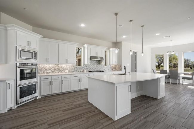 Kitchen with appliances with stainless steel finishes, a sink, backsplash, white cabinets, and recessed lighting | Image 4