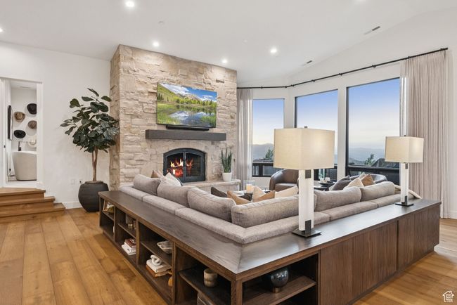 Living room featuring light wood-type flooring, vaulted ceiling, recessed lighting, and a fireplace | Image 16