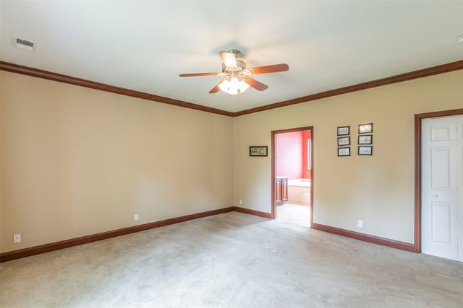 Empty room with light colored carpet, crown molding, baseboards, and ceiling fan | Image 12