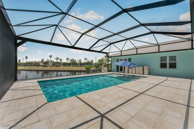 Outdoor pool featuring a patio area, a water view, and glass enclosure | Image 33