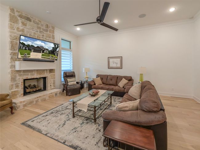 Living area with ornamental molding, light wood-style flooring, a ceiling fan, a fireplace, and recessed lighting | Image 4