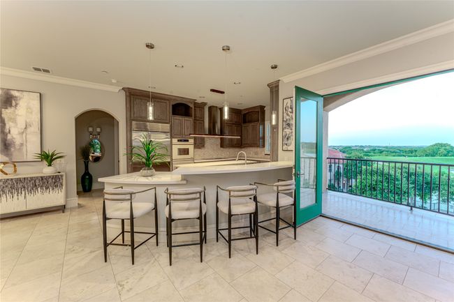 Kitchen with white oven, built in fridge, arched walkways, decorative backsplash, and light countertops | Image 16