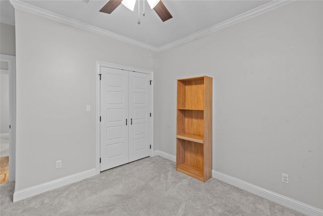 Unfurnished bedroom with crown molding, carpet flooring, a closet, and a ceiling fan | Image 16