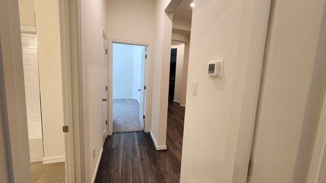 Corridor featuring dark wood-style floors, a textured wall, and baseboards | Image 11