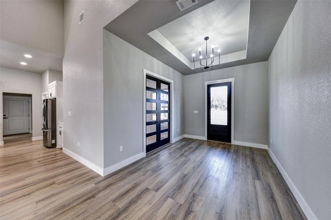 Entrance foyer featuring french doors, light wood-type flooring, a raised ceiling, and a notable chandelier | Image 22