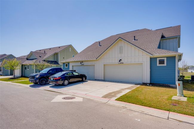 View of front of property featuring a shingled roof, a garage, board and batten siding, and concrete driveway | Image 26