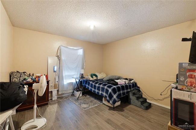 Bedroom with wood finished floors and a textured ceiling | Image 6