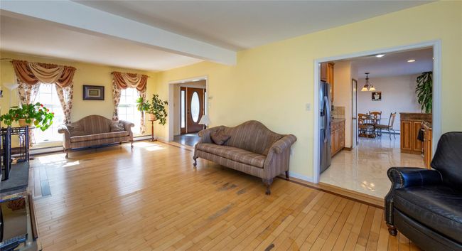 Living room with light wood-style flooring, baseboards, baseboard heating, and beam ceiling | Image 19