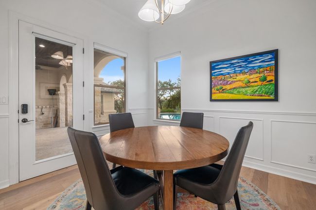 Dining space featuring ornamental molding, light wood-type flooring, a chandelier, a decorative wall, and a wainscoted wall | Image 11