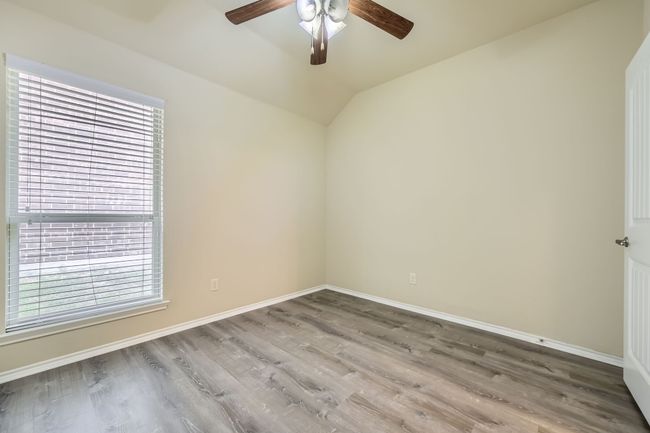 Unfurnished room featuring a ceiling fan, healthy amount of natural light, wood finished floors, and lofted ceiling | Image 21