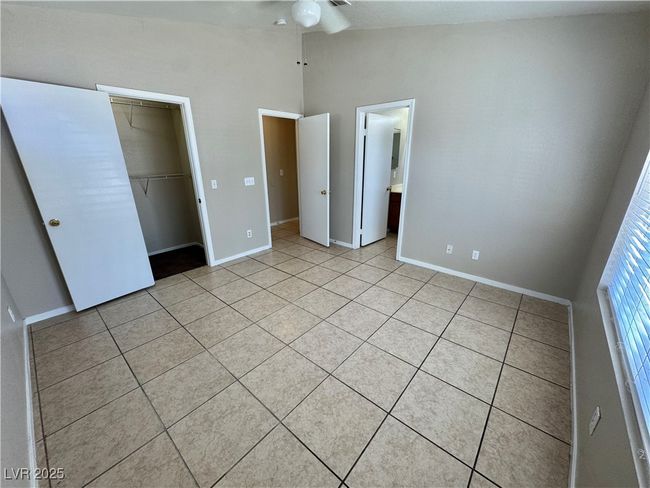 Unfurnished bedroom featuring lofted ceiling, baseboards, a closet, and light tile patterned floors | Image 11