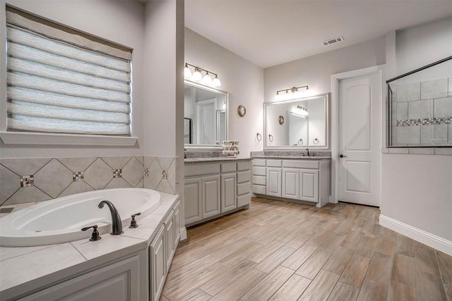 Full bath featuring two vanities, a bath, and wood finished floors | Image 36