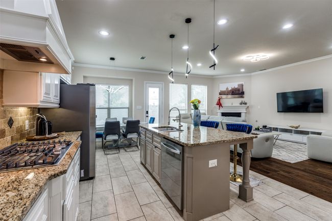 Kitchen with appliances with stainless steel finishes, open floor plan, crown molding, a fireplace, and a breakfast bar area | Image 10
