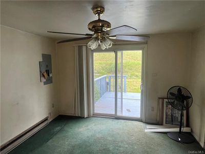 Unfurnished room featuring carpet, electric panel, a baseboard heating unit, and ceiling fan | Image 2