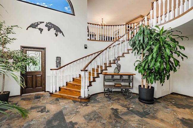 Foyer entrance featuring a high ceiling, stairway, stone tile floors, and a chandelier | Image 4