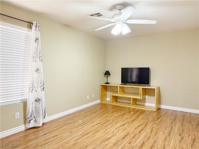 Unfurnished living room with visible vents, baseboards, wood finished floors, and ceiling fan | Image 13