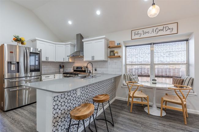 Kitchen with wall chimney range hood, stainless steel appliances, a sink, dark wood-style floors, and vaulted ceiling | Image 11