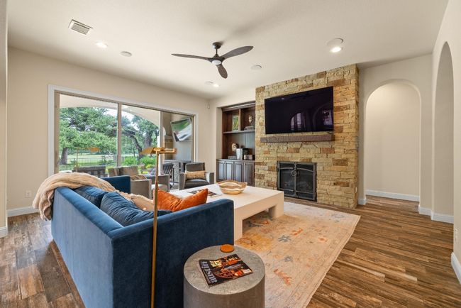 Living room with ceiling fan, wood finished floors, baseboards, a fireplace, and recessed lighting | Image 10